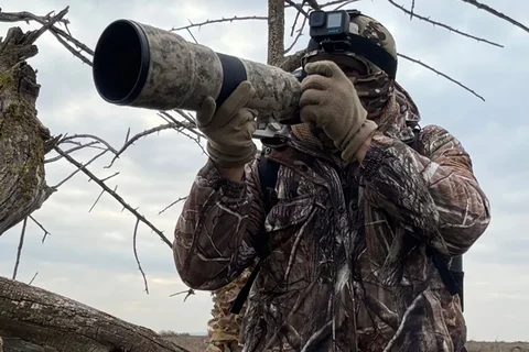 Wildlife photographer using a long telephoto lens outdoors